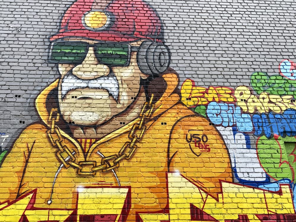 Portrait de mineur avec casque et lampe frontale peint sur un mur de la cité minière de Lens