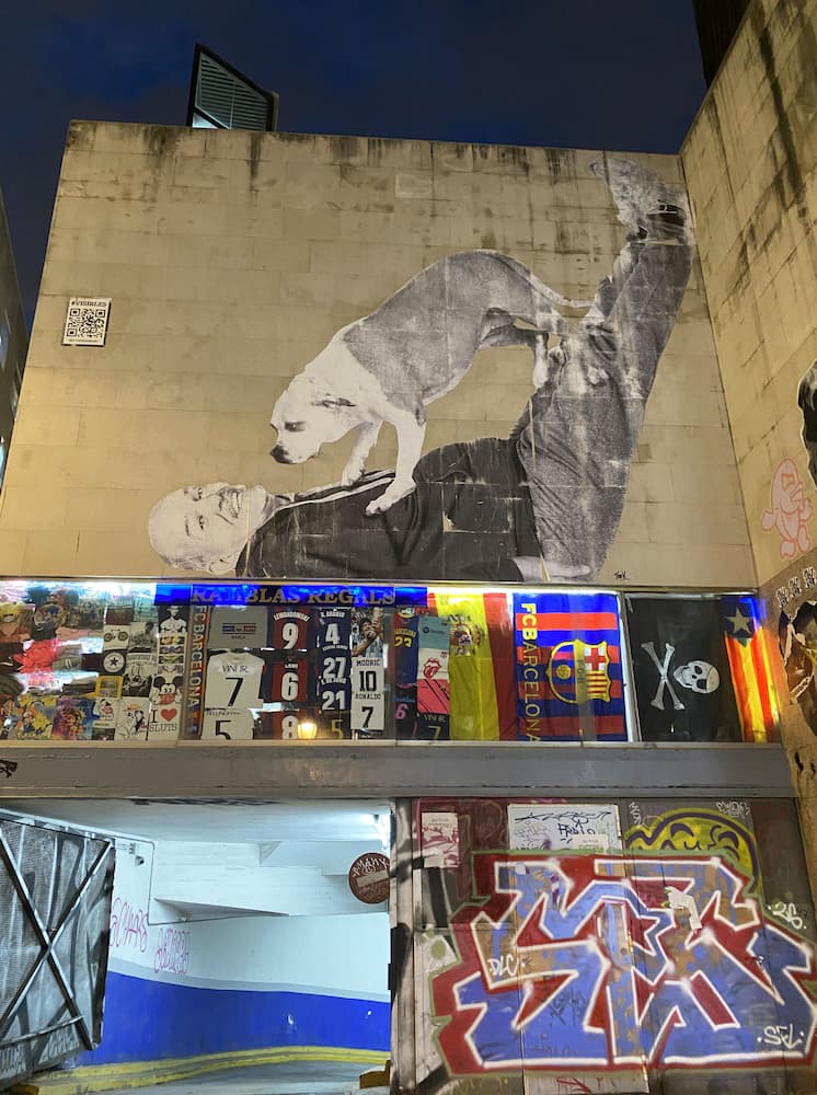 Collage mural représentant un homme et son chien dans une ruelle du quartier gothique de Barcelone